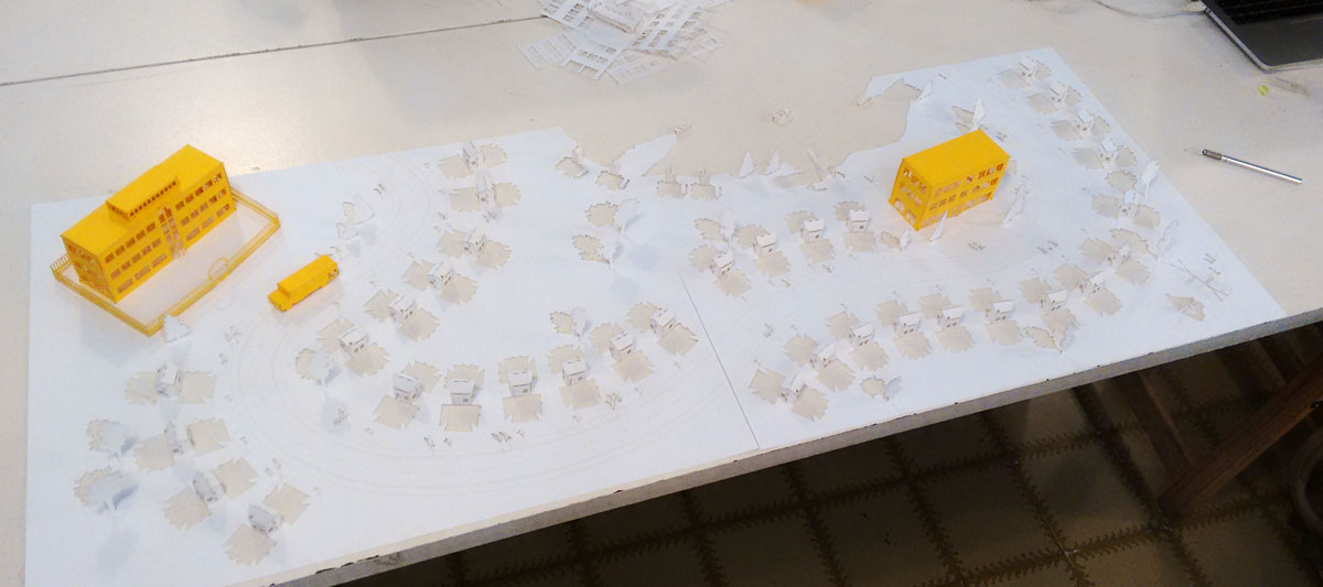 Una maqueta de papel blanco de un pueblecito de casas pequeñas encima de una mesa de plástico blanco